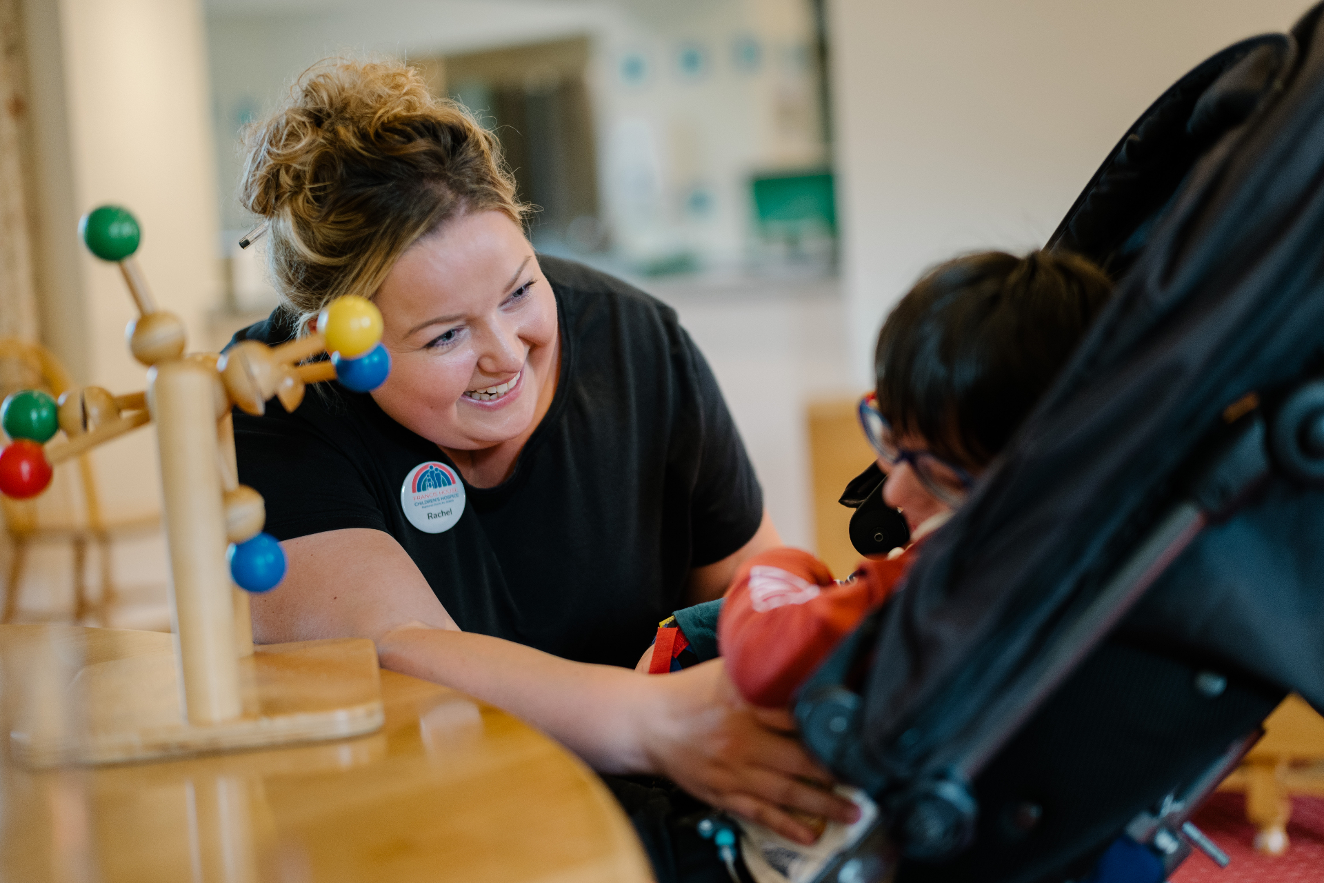 A hospice play therapist smiling with a child at Francis House Children's Hospice