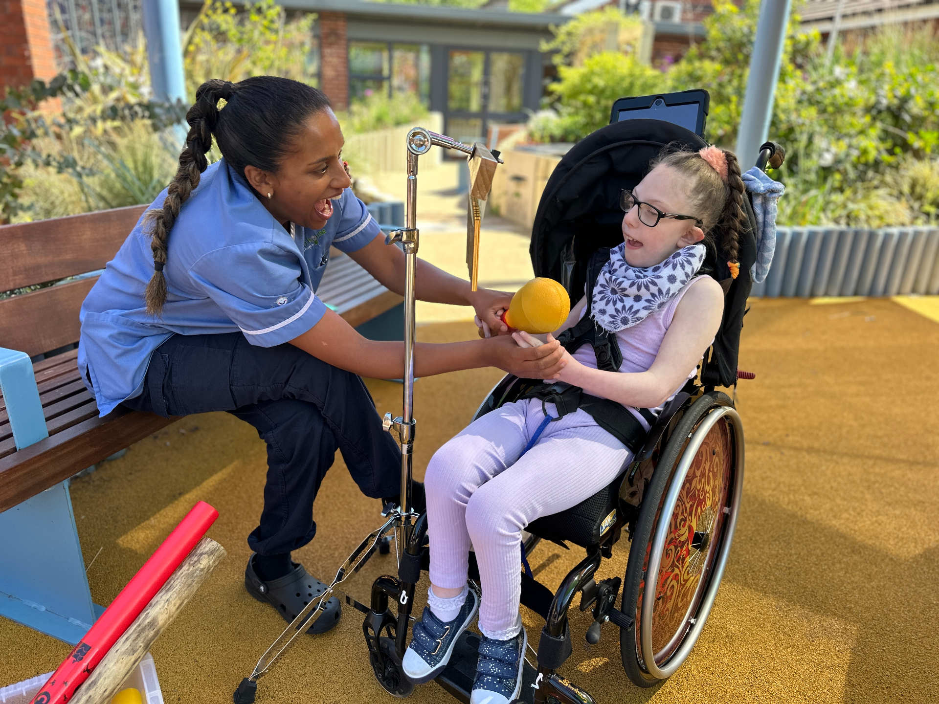 Children's hospice nurse playing music with a young girl in a wheelchair